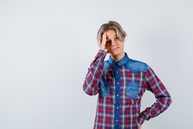 Young teen boy suffering from headache in checked shirt and looking distressed. front view.
