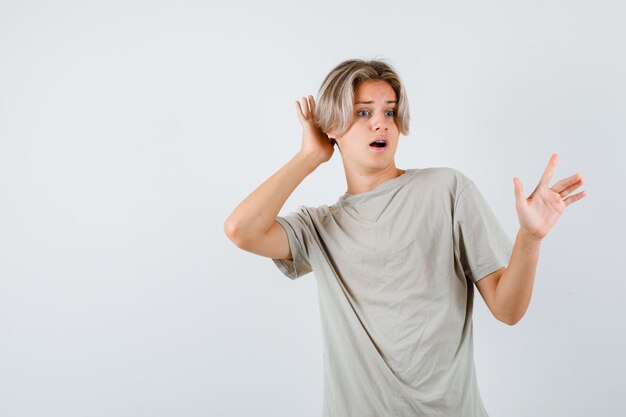 Young teen boy in t-shirt keeping hand behind head