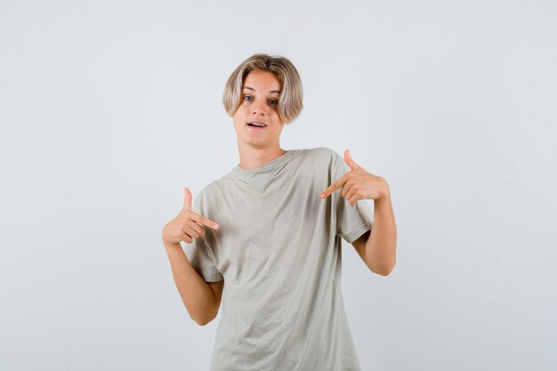 Young teen boy in t-shirt pointing at himself and looking merry , front view.
