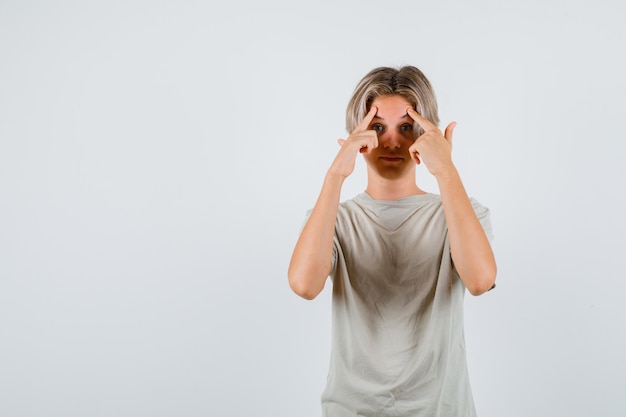 Young teen boy in t-shirt pointing at his forehead and looking smart , front view.