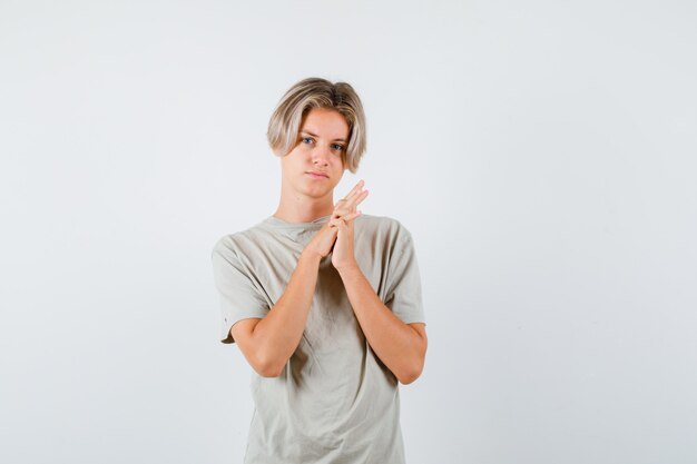 Young teen boy in t-shirt pressing hands together and looking thoughtful , front view.