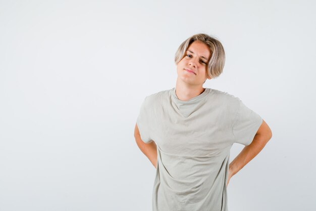 Young teen boy in t-shirt suffering from backache and looking exhausted , front view.