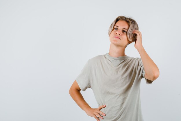 Young teen boy in t-shirt with hand on head