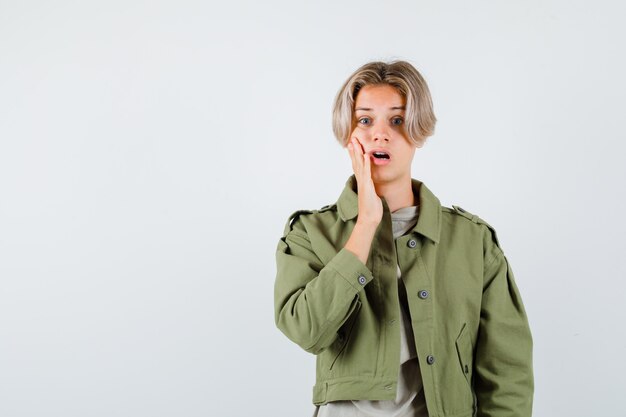 Young teen boy with hand on cheek in t-shirt