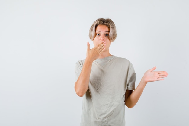 Young teen boy with hand on mouth