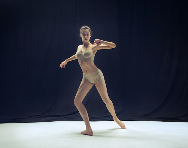 白い床のスタジオの背景で踊る若い十代のダンサー。バレリーナプロジェクト。