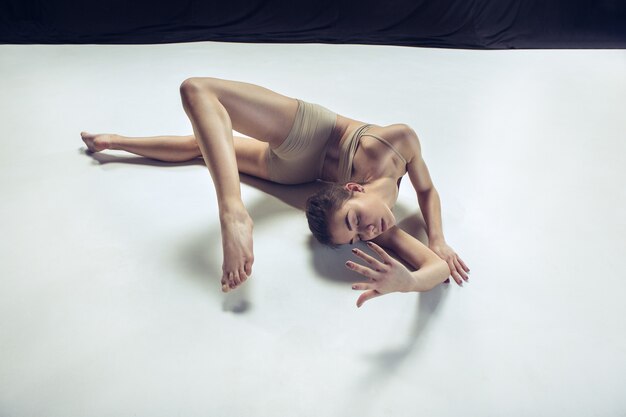 Young teen dancer dancing on white floor studio background. Ballerina project.