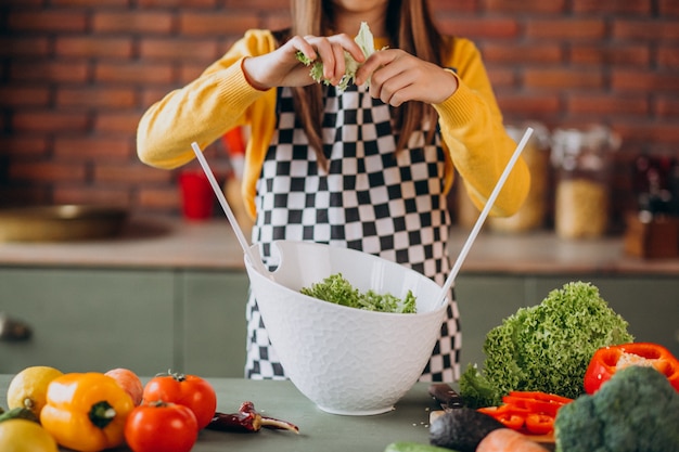 Giovane ragazza teenager che prepara insalata per la prima colazione alla cucina