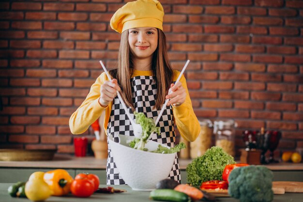 Young teen girl preparing salad for breakfast at the kitchen