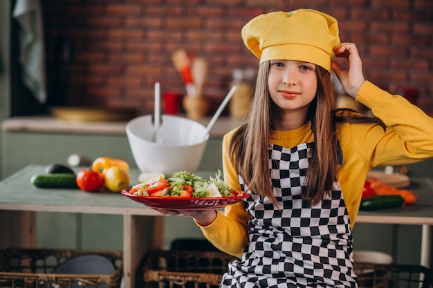 キッチンで朝食のサラダを準備する若い十代の少女