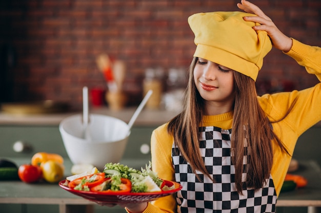 キッチンで朝食のサラダを準備する若い十代の少女