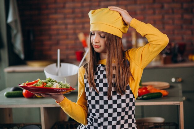 キッチンで朝食のサラダを準備する若い十代の少女