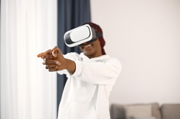 Young teenage girl standing in living room wearing a virtual reality glasses