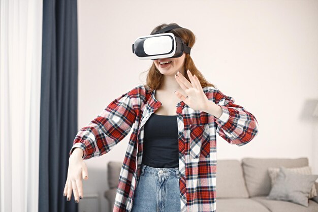 Young teenage girl standing in living room wearing a virtual reality glasses