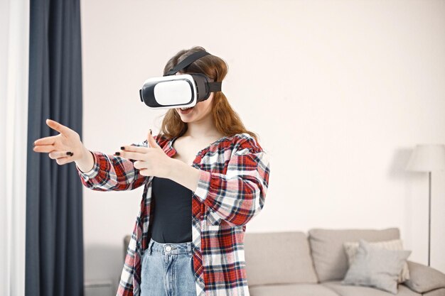 Young teenage girl standing in living room wearing a virtual reality glasses