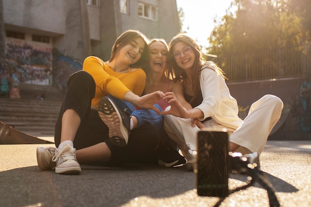 Foto gratuita giovani ragazze adolescenti che registrano bobine di se stesse all'aperto per i social media