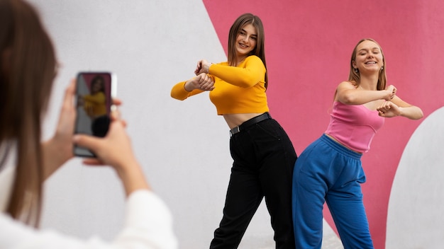 Young teenage girls recording reels of themselves outdoors for social media