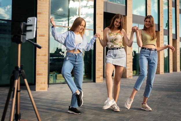 Young teenage girls recording reels of themselves outdoors for social media