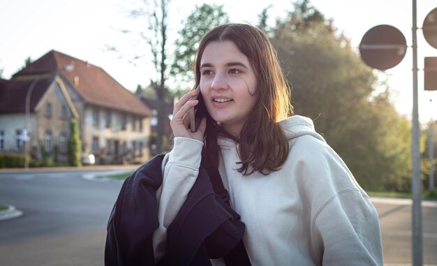 A young teenage woman is waiting for a bus at a bus stop early in the morning