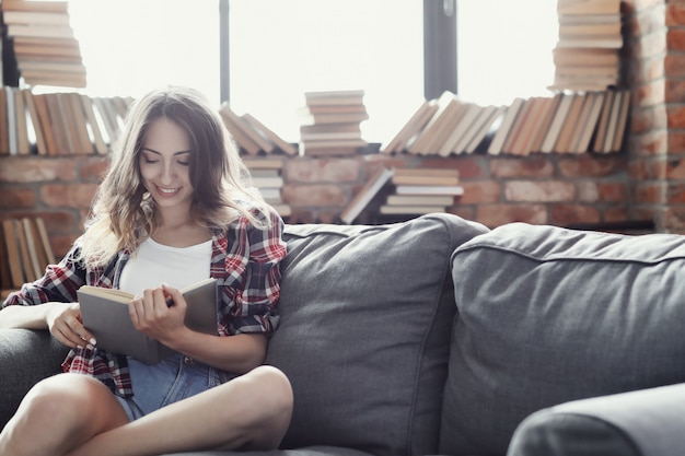 Молодая девушка подростка читая книгу дома