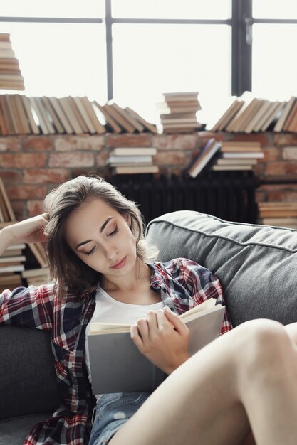 Молодая девушка-подросток, читающая книгу дома