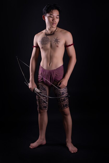 young THAILAND male warrior posing in a fighting stance with a bow