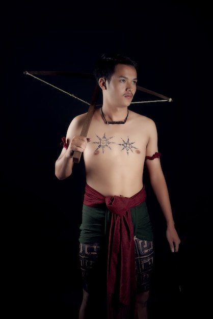 young THAILAND male warrior posing in a fighting stance with a crossbow
