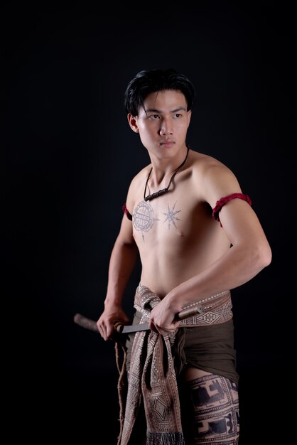 young THAILAND male warrior posing in a fighting stance with a sword