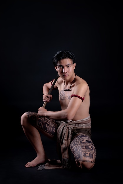 young THAILAND male warrior posing in a fighting stance with a sword