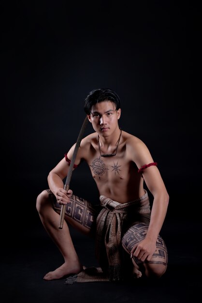 young THAILAND male warrior posing in a fighting stance with a sword