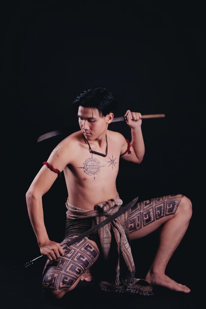 young THAILAND male warrior posing in a fighting stance with a sword