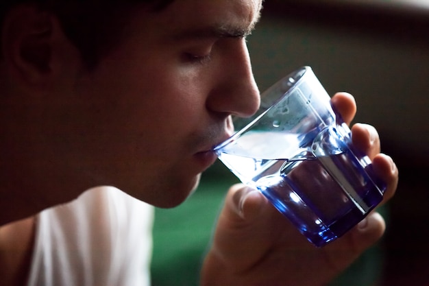 Free photo young thirsty dehydrated man drinking water quenching thirst, closeup view