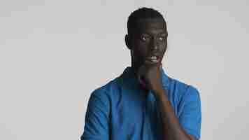 Free photo young thoughtful african american man rubbing chin thinking on camera over white background deep in thought expression