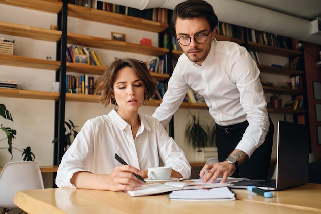 Young thoughtful business colleagues working on new project with laptop in modern office