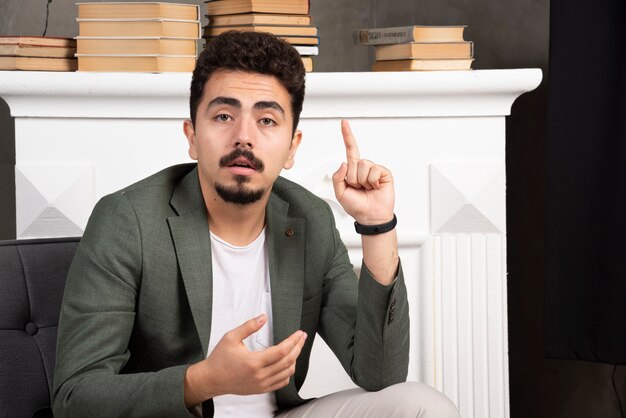 Young thoughtful man pointing his finger up.