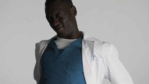 Free photo young tired african american male doctor in uniform doing physical jerks on camera over white background