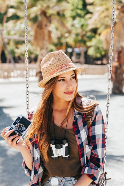 Young tourist posing with camera on the swing