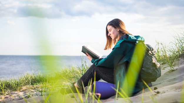 Young tourist reading book near sea