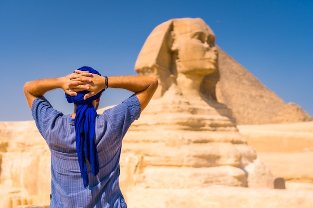 ギザの大スフィンクス、カイロ、エジプトの近くに立っている青いターバンを身に着けている若い観光客