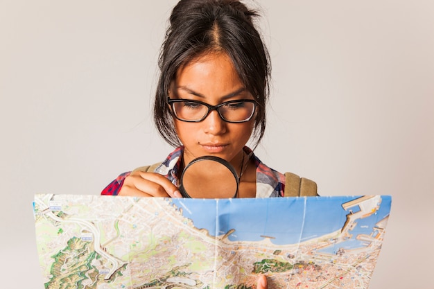 虫眼鏡と地図を持つ若い観光客の女性
