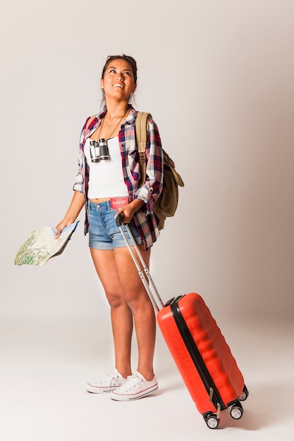 Young tourist woman with suitcase looking around