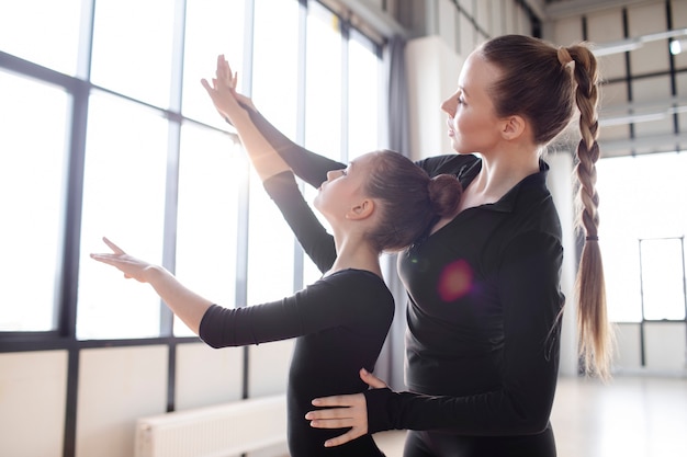 Free photo young trainer helping trainees in practicing gymnastics