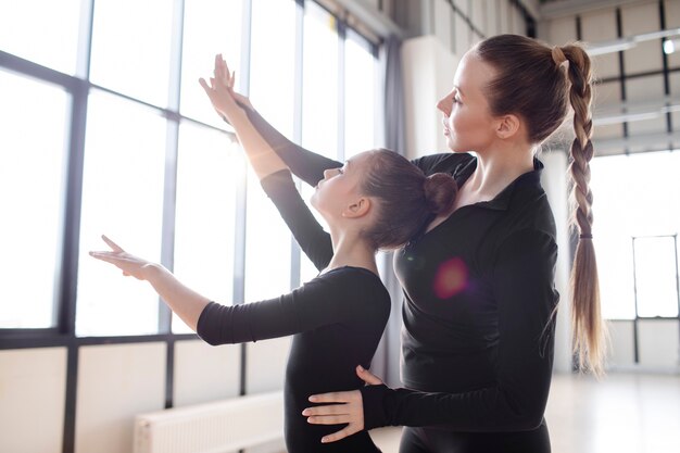 Young trainer helping trainees in practicing gymnastics