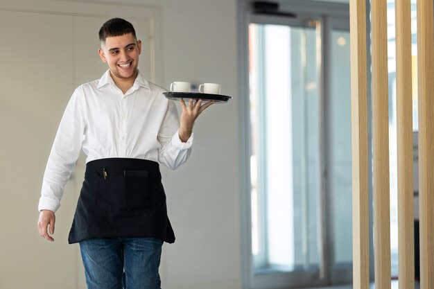 Young trans man with apron working as a waiter