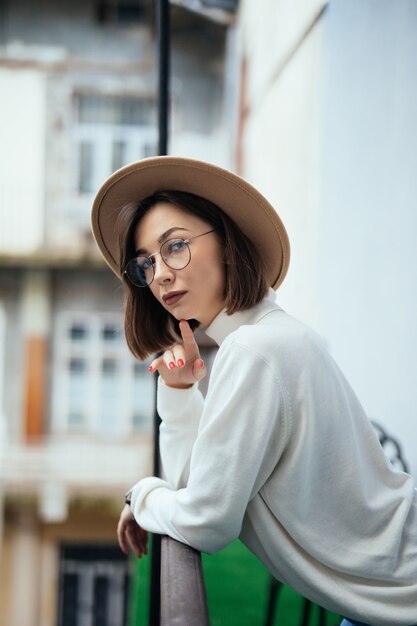 Young in transparent glasses and hat staying at balcony