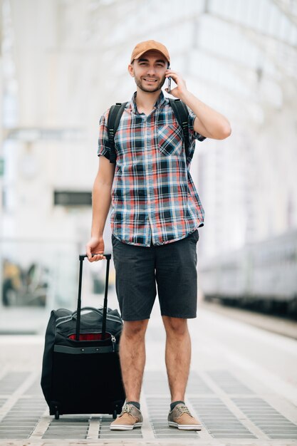 Young traveler man talking on the phone at the train station