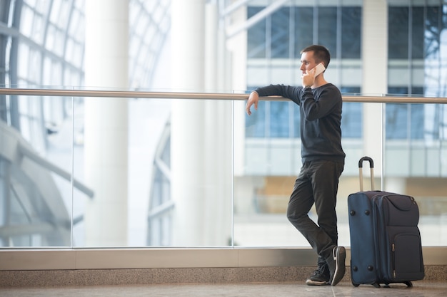 Foto gratuita giovane, viaggiatore, parlare, smartphone, aeroporto