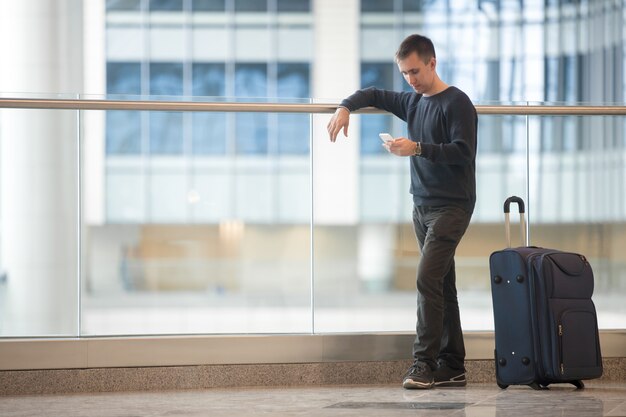 空港でスマートフォンを使用している若い旅行者