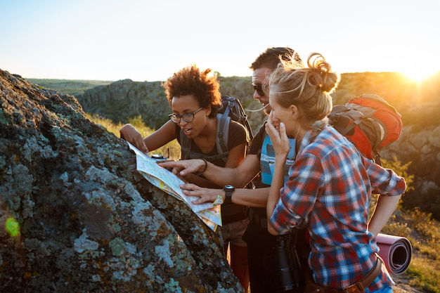 Young travelers with backpacks smiling, looking for route on map