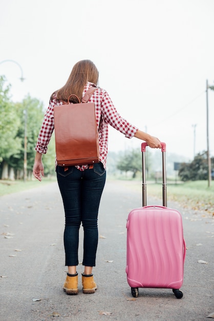 Foto gratuita giovane viaggiatore con zaino e bagagli rosa